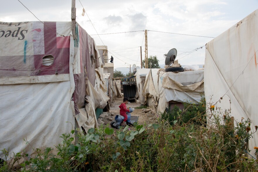 A Syrian child plays outside his tent in the informal refugee settlement where Fatmeh lives with her family in eastern Lebanon's Beqaa Valley.