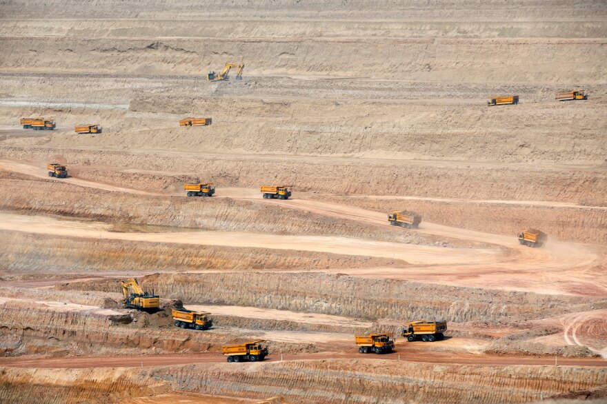 Dump trucks drive at the open-pit coal mining site in Islamkot, in the Thar desert in Pakistan in 2017.
