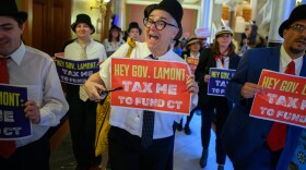 Hartford, Ct. — April 15, 2026 — Protestors dressed as Mr. Monopoly, march through The Capitol on Tax Day, April 15, 2026, to deliver postcards petitioning Governor Lamont to raise taxes on the wealthy.
