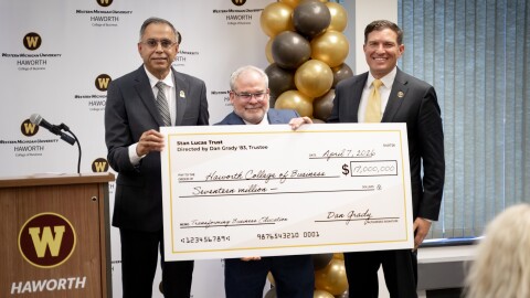 Three men stand next to a podium bearing the WMU logo and "Haworth", with a white WMU backdrop behind them. They hold a large check for $17 million dollars.