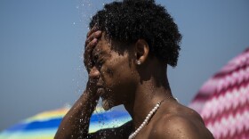 man standing on a beach splashing water on his face