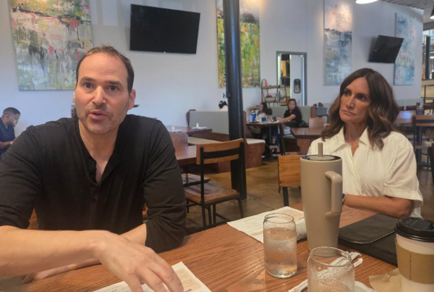 Man and woman sit at table, man speaks