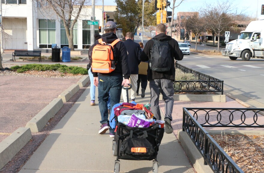 A group of volunteers wheel a wagon full of supplies down the sidewalk in downtown Sioux Falls. 