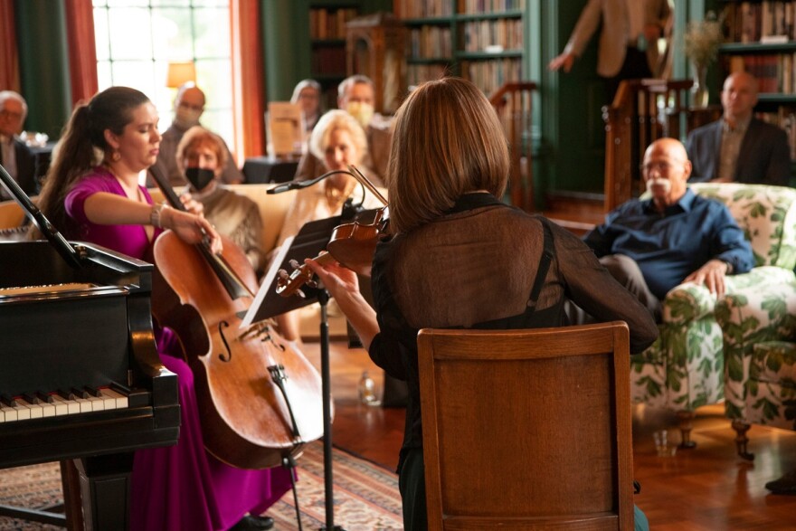 Two string players performing for an audience in a library