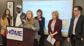 Partnership for the Public Good Executive Director Andrea Ó Súilleabháin, standing at lectern, lays out her concerns with how long it often takes the state to make payments for contracts with nonprofit organizations.