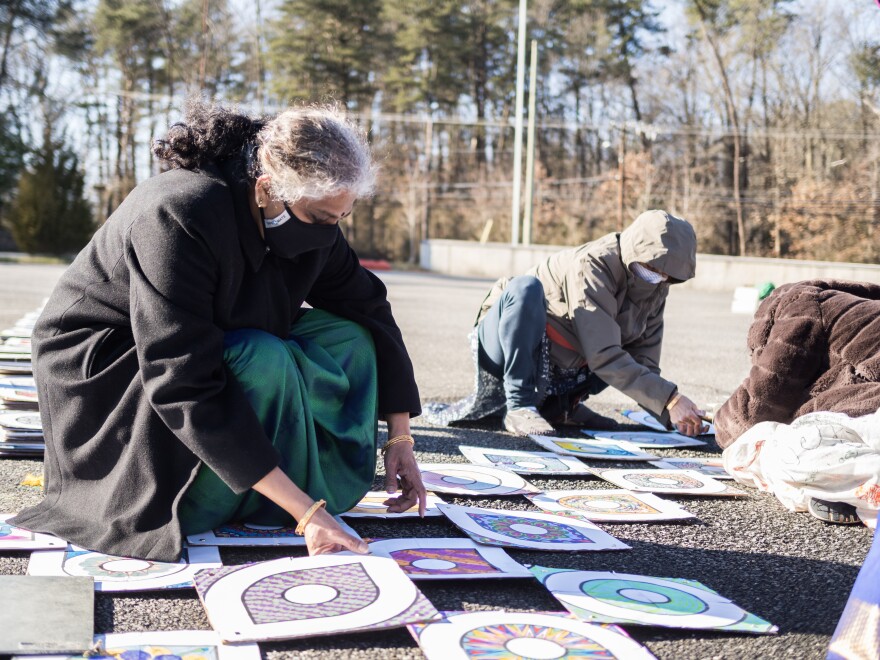 Volunteers assemble a rendition of the inauguration kolam using recycled paper and cardboard. The kolam is a traditional South Indian art form used as a sign of welcome.