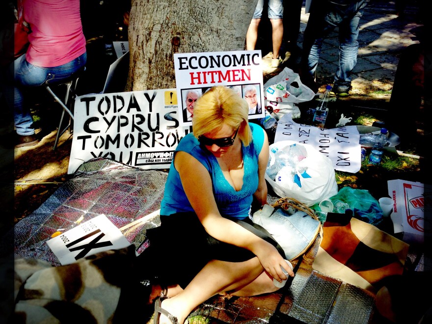 A Cypriot left-wing supporter sits in the shade during a protest outside the Parliament in Nicosia on Tuesday.