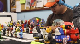 Viet Huynh, a vendor and artist at Gamesville Tabletop’s flea market, works on crafting figurines while displaying his figures for people to buy. (Nicole Needles/WUFT News)