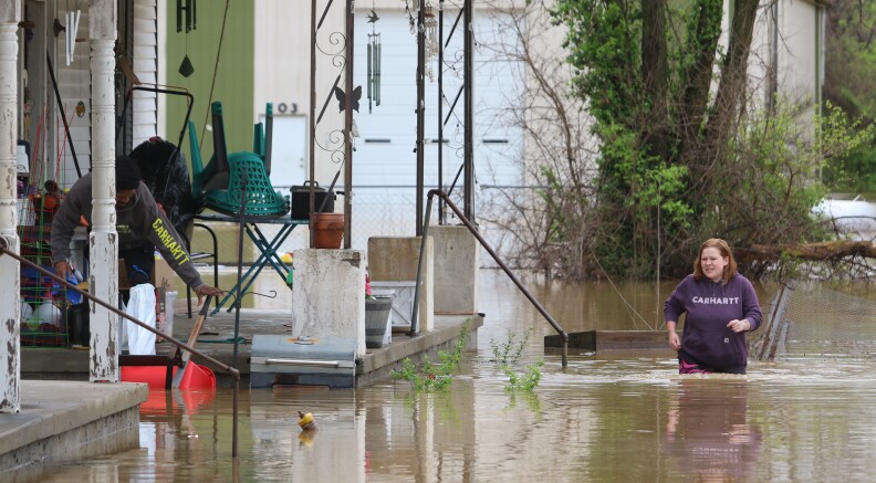 A woman walks through floodwaters near a home off Seventh Street in Hopkinsville on Friday.