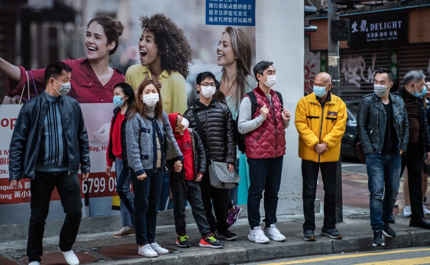 For societies that were affected by the SARS epidemic, the widespread usage of masks was more quickly adopted during the spread of COVID-19. Photograph of people waiting to cross the street in the Causeway Bay neighborhood of Hong Kong, Monday, January 27, 2020.