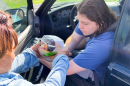 A volunteer with Wings of Faith Fellowship Church in Silver Springs Shores hands pastries to Conner Ortiz during a food distribution at the church last month.