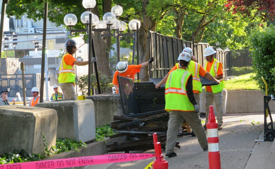 Workers removing sections of fencing. 