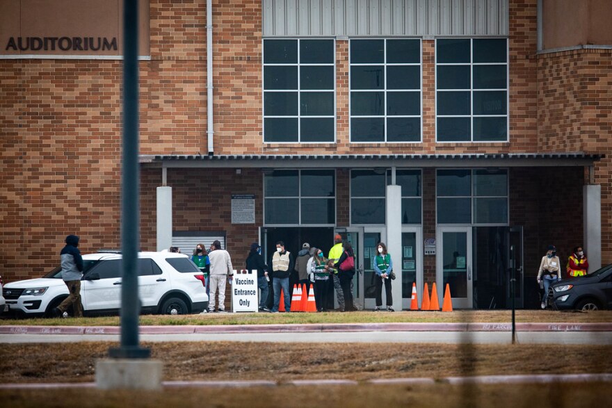 People wait outside San Marcos High School during a COVID-19 vaccination clinic.