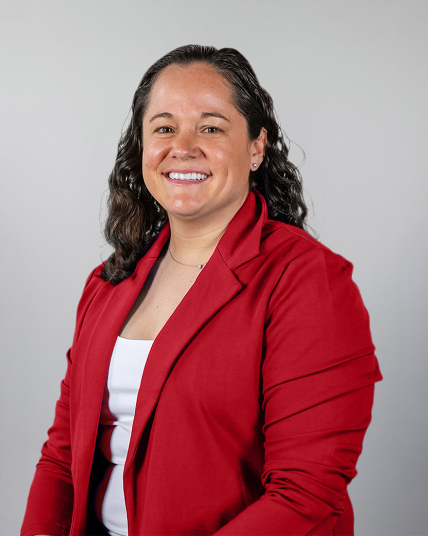 A woman wearing a red blazer and white top smiles in a headshot against a light gray background.