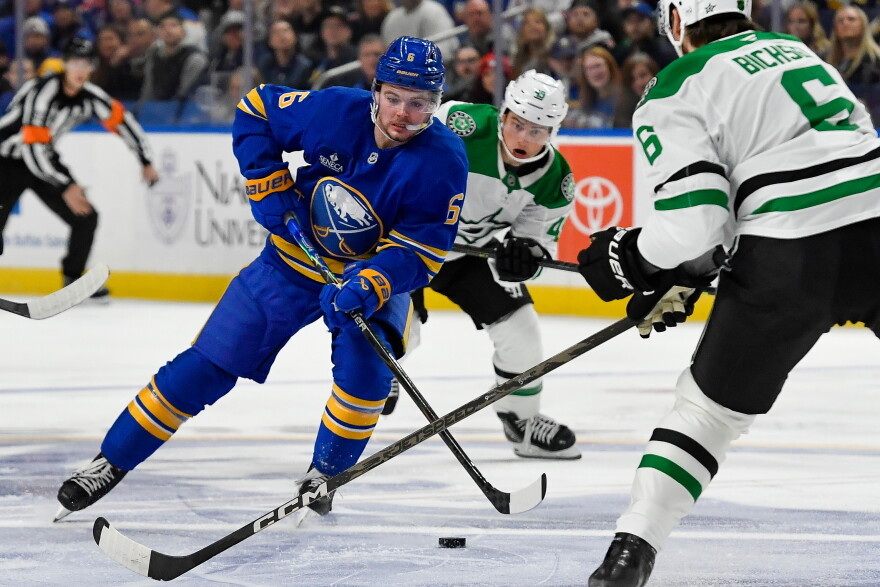 Buffalo Sabres left wing Zach Benson, left, skates the puck between Dallas Stars center Justin Hryckowian, center, and defenseman Lian Bichsel, right, during the first period of an NHL hockey game Thursday, Oct. 8, 2026, in Buffalo, N.Y. (AP Photo/Adrian Kraus)