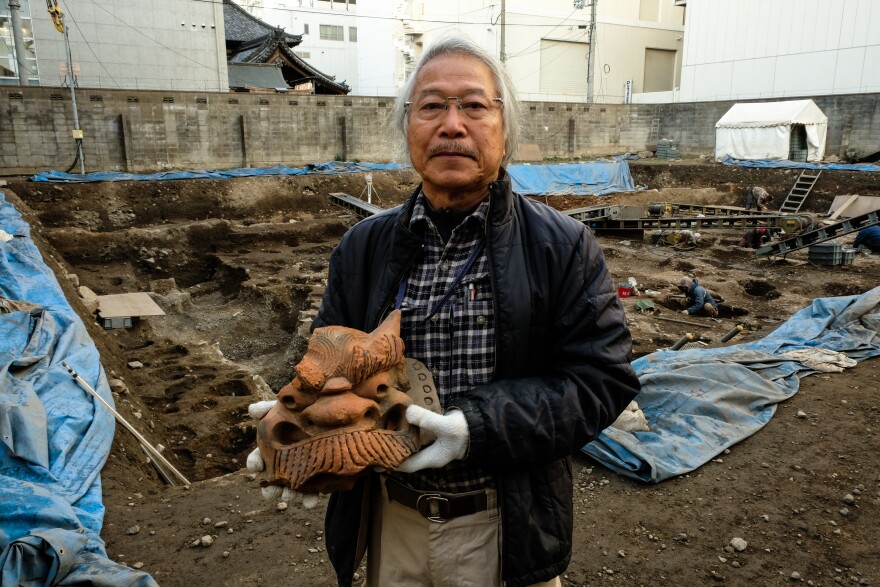 Archaeologist Koji Iesaki holds a carved roof ornament excavated at the former site of the Jyokyo-ji temple in Kyoto, Japan. Iesaki and other archaeologists have their hands full as a pre-Olympic building boom has helped reveal centuries-old artifacts from the city's long history.