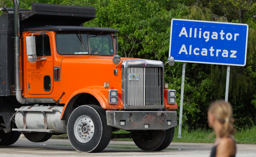 Dump trucks move in and out of Alligator Alcatraz during an hour-long prayer vigil on Sunday, Sept. 21, as attendees watch.