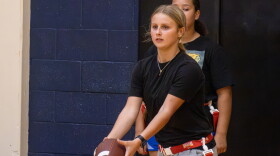Wichita Northwest High School sophomore Bella Scott practices hand-off drills inside the school's gym on Monday afternoon. The school's flag football team is one of many athletic programs taking practice indoors amid extreme heat.