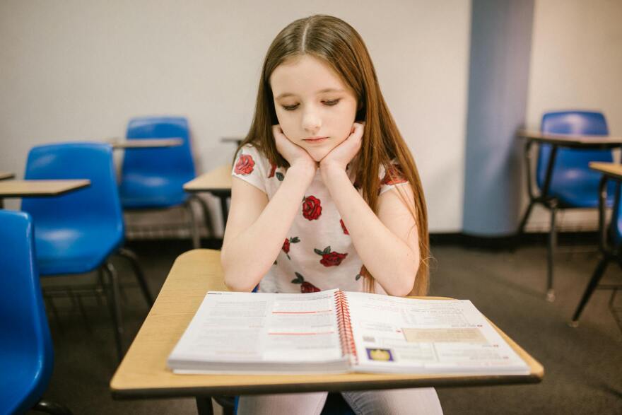 Girl sitting on her desk looking lonely.
