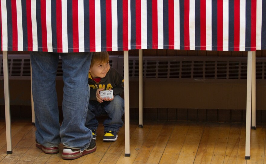 Cameron Carbone, 4, peeks out of the voting booth as his father votes in Wilton. 