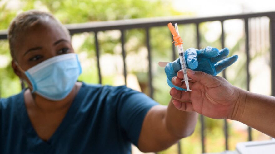A nurse is handed a dose of the Pfizer COVID-19 vaccine before administering it to a college student during a mobile vaccination clinic at California State University, Long Beach on Aug. 11.