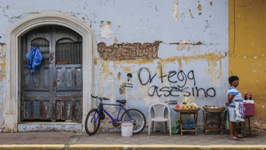 A woman sells refreshments in front of graffiti that reads "Ortega murderer!" in Granada, Nicaragua, last week. The city's tourism industry has grown anemic since the wave of protests broke out in April.