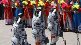 Chinese astronauts (from left) Wang Yaping, mission commander Nie Haisheng and Zhang Xiaoguang gesture as they prepare to board the Shenzhou-10 spacecraft in Jiuquan, China, on Tuesday.