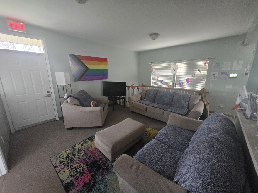 A living room is furnished with couches and decorated with rainbow flags.