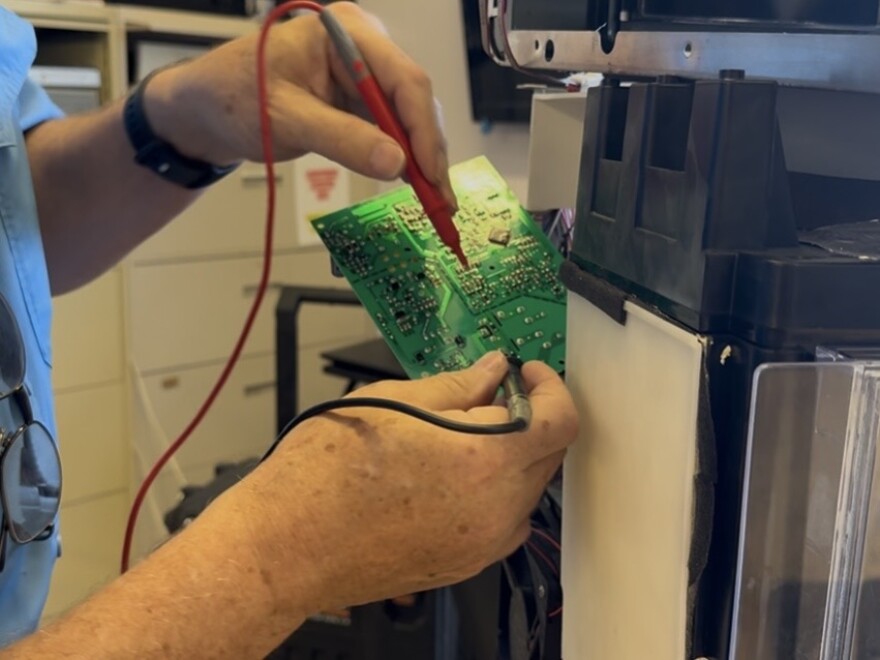 A Hackerspace volunteer works on the electronic board of a 3D printer.