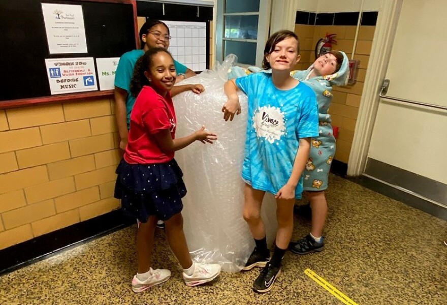 Park Road Montessori students (l-r) Zoe Satterfield, Candace Ramet, Zoe Ireland and Miska Swartz with a big roll of bubble wrap.