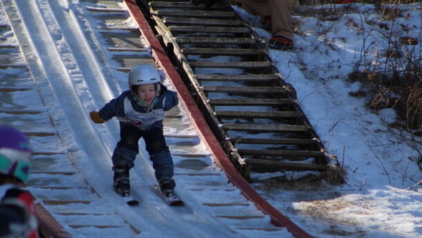 A young girl smiles as she skis down the 8-meter Red Wing Hill at Mount Itasca on Feb. 17, 2024.