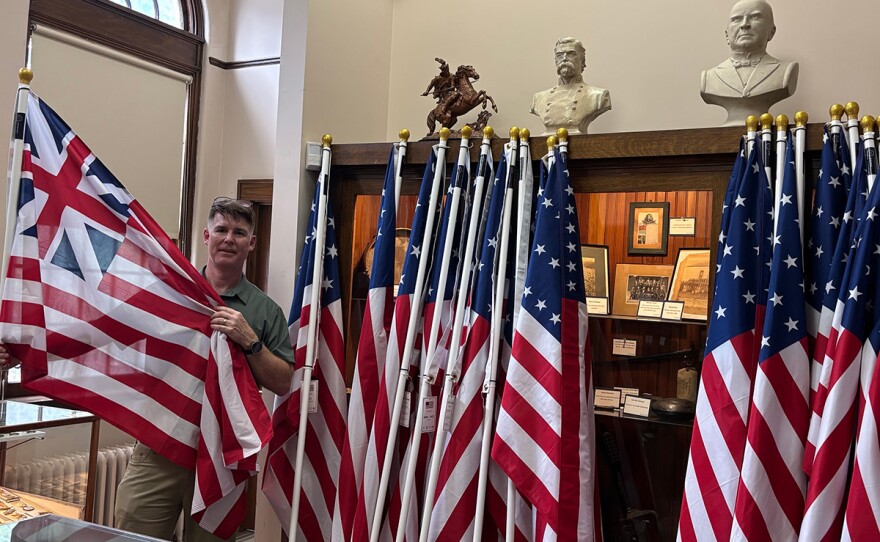 A man stands with American flags