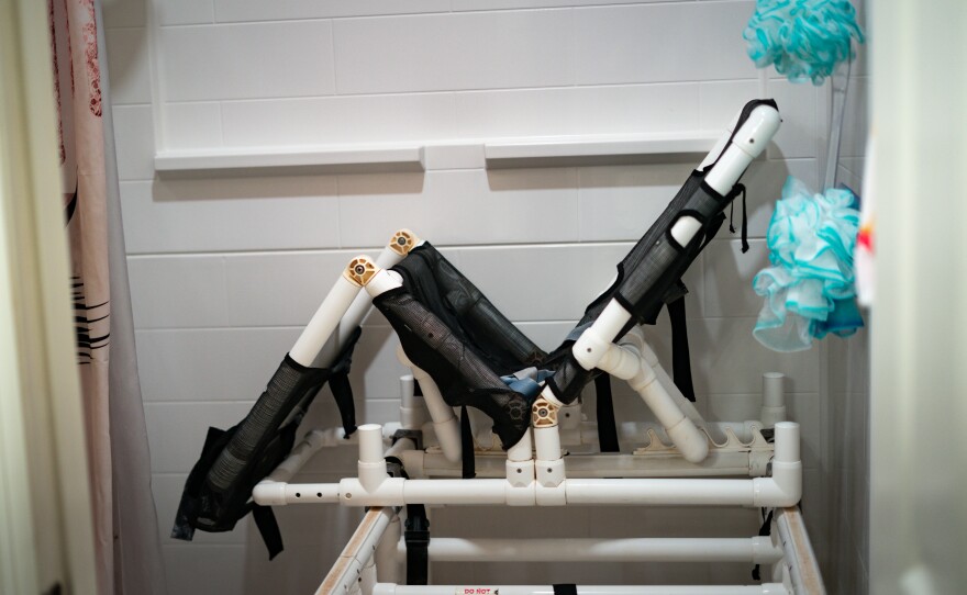 A white and silver metal shower chair in a shower