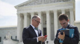 Jim Obergefell (C), the lead plaintiff in the same-sex marriage case Obergefell v. Hodges, the case that could determine the constitutionality of marriage for same-sex couples, checks his phone as he walks out of the US Supreme Court in Washington, DC.