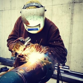 A welder working on a piece of steel tubing. Welding is one of the skills taught through the Building Trades pathway at the Southwest Colorado Education Collaborative.