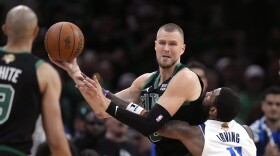 Boston Celtics center Kristaps Porzingis looks to pass while defended by Dallas Mavericks guard Kyrie Irving (11) during the second half of Game 2 of the NBA Finals basketball series, Sunday, June 9, 2024, in Boston. (AP Photo/Steven Senne)