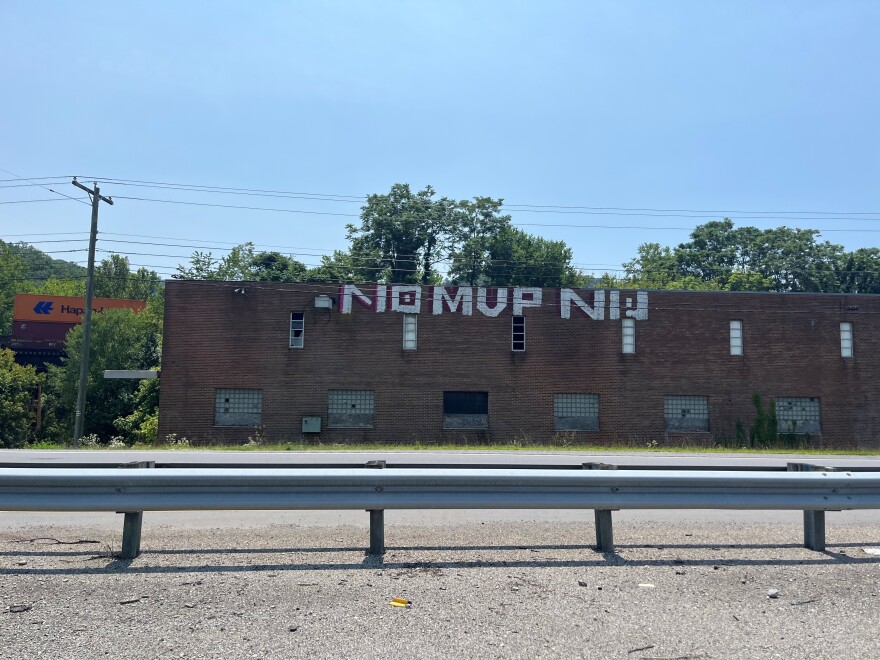 A highway with the words 'No MVP NW' painted on the side of a brick building. 