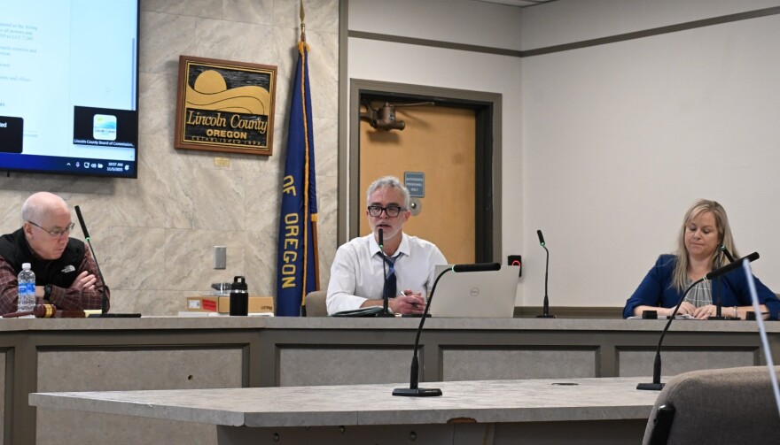 Three people sitting at a dais during a public meeting. 