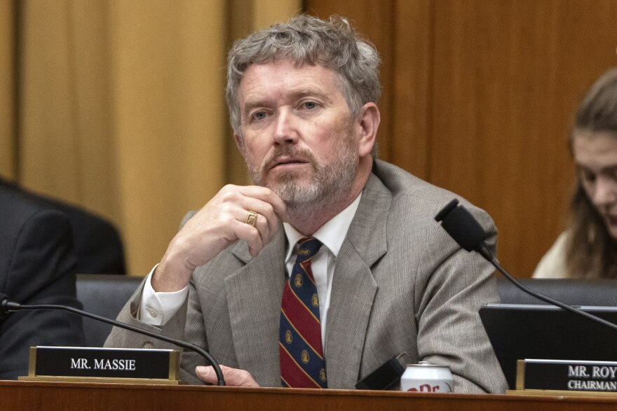 a man in a suit holds his hand to his chin while listening
