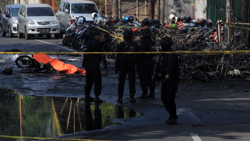 Indonesian anti-terror policeman stands guard at the blast site following a suicide bomb outside a church in Surabaya, Indonesia on Sunday.