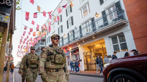 Walking under flags that memorialize victims of Jan. 1, 2025 attack, members of the Louisiana National Guard, military police, and Louisiana law enforcement agencies patrol the French Quarter along Bourbon Street and intersecting streets as part of a National Guard deployment for New Year's celebrations in New Orleans, Tuesday, Dec. 30, 2025. (AP Photo/Matthew Hinton)