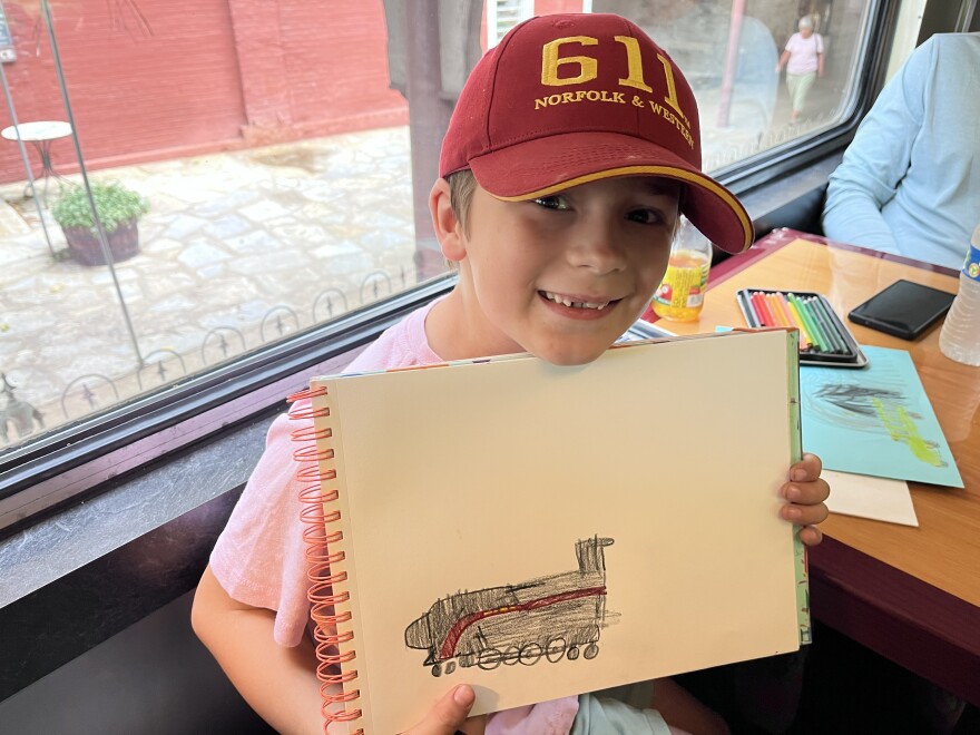 Xavier, a young 611 fan, draws the historic locomotive as he waits for the train to depart the Staunton station.