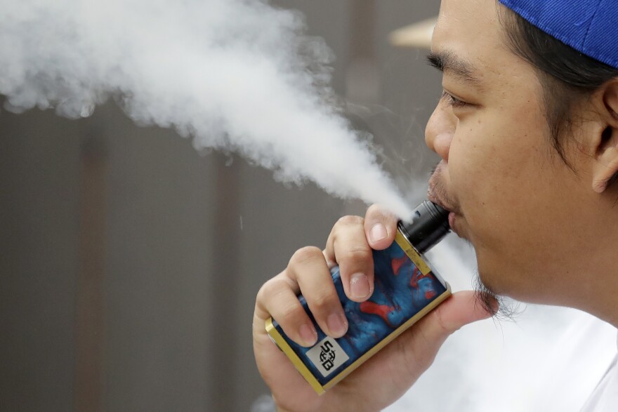 FILE - This Dec. 11, 2019, file photo shows a cloud of vapor being released from an electronic cigarette by a man in Tukwila, Wash. (AP Photo/Elaine Thompson, File)