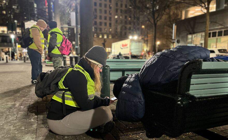 A surveyor, talking to a homeless man, in uptown Charlotte on Jan. 23.