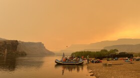 Rafters rig their boats under the orange glow of wildfire smoke Saturday. Within Grand Canyon National Park, all corridor trails remain closed except for those joining or leaving river trips. Boat Beach has reopened for river runners to stop and refill water; however, they must continue to Pipe Creek beach for passenger exchanges.