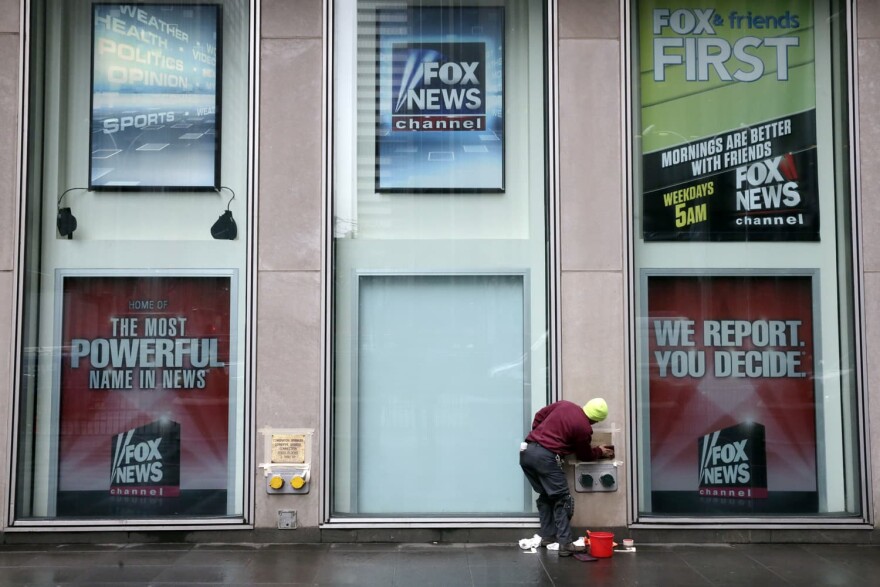 A worker cleans a sign outside the Fox television studios, where a poster of Bill O'Reilly has been removed, in New York.
 (Richard Drew/AP)