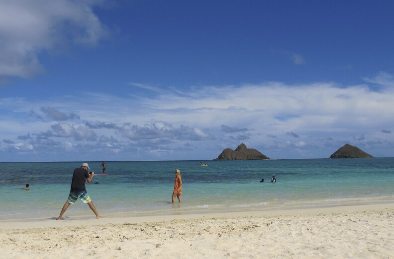 FILE - This Oct. 29, 2013 file photo shows tourists on Lanikai Beach in Kailua, Hawaiʻi, a town with a large number of vacation rentals. (AP Photo/Audrey McAvoy)