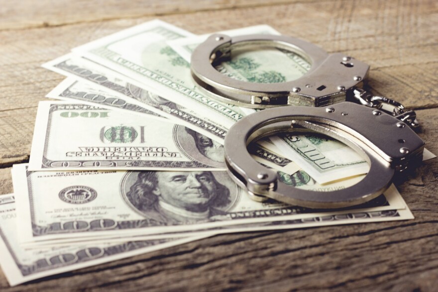 handcuffs sit atop half a dozen 100 dollar bills