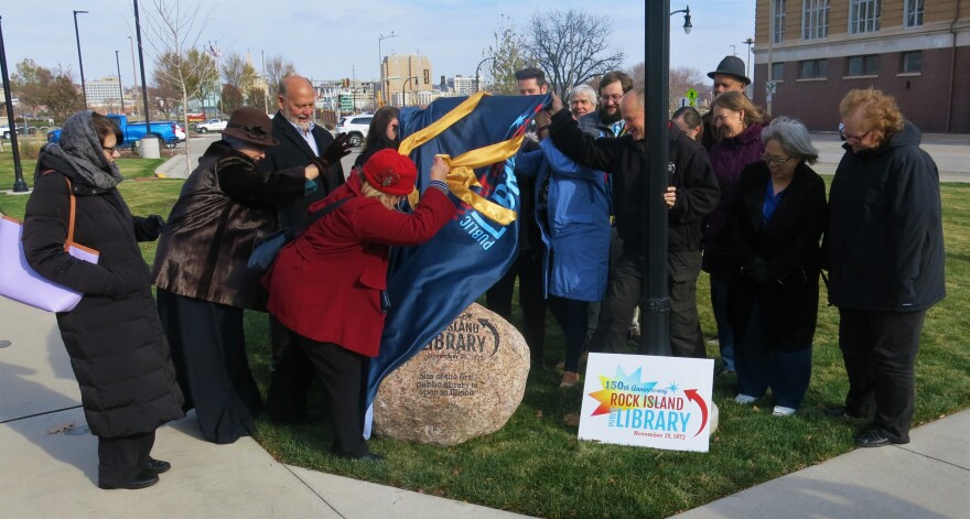 library staff and city officials unveil the monument at the site of the first library