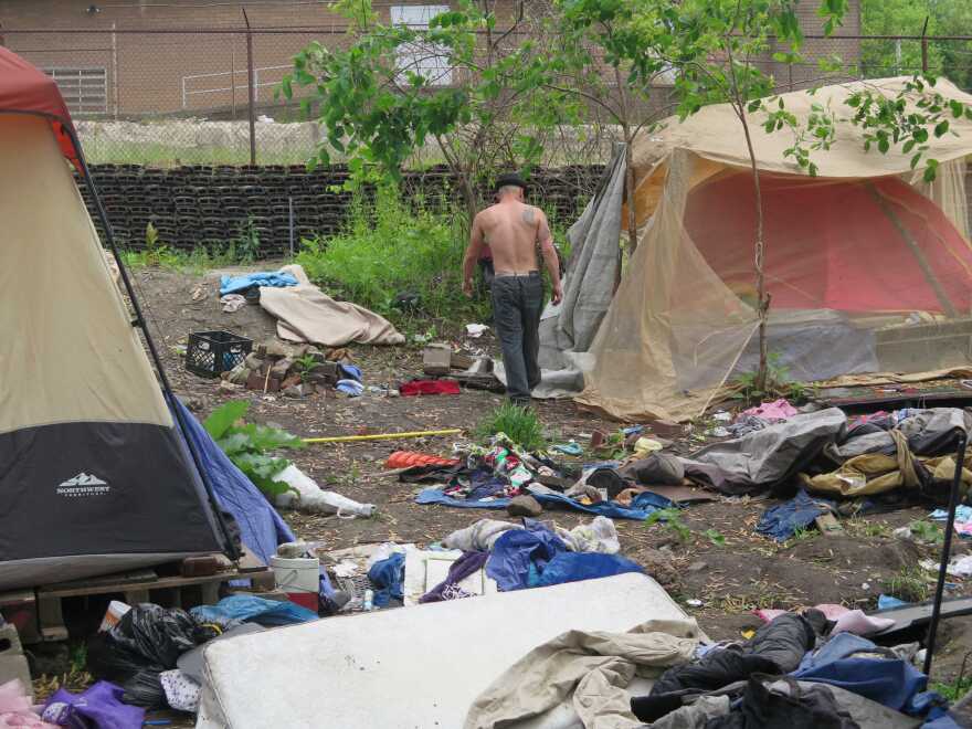 A homeless resident searches for belongings at replacement site for Tent Village in Akron’s Middlebury neighborhood. [Rick Jackson / ideastream]